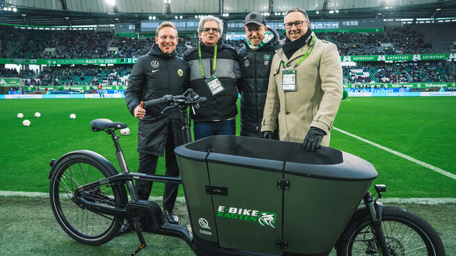 Die Fans des VfL Wolfsburg bekommen ein E-Bike überreicht.