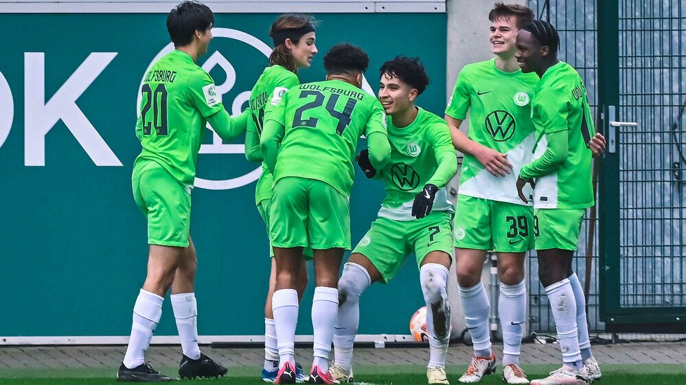 Die Nachwuchsspieler des VfL Wolfsburg stehen jubelnd beisammen.