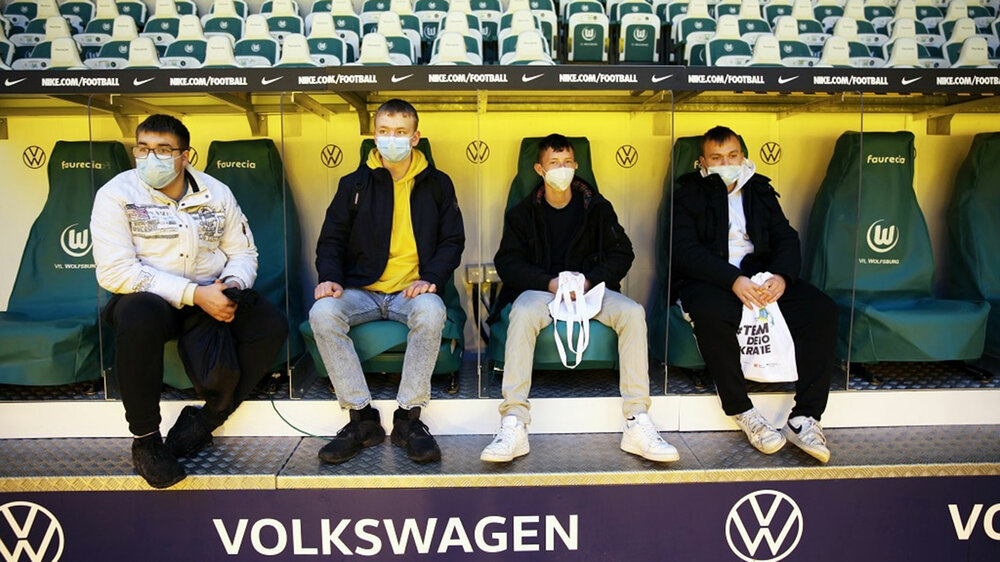 Jugendliche VFL Wolfsburg Fans sitzen auf der Trainerbank in der Volkswagen Arena.