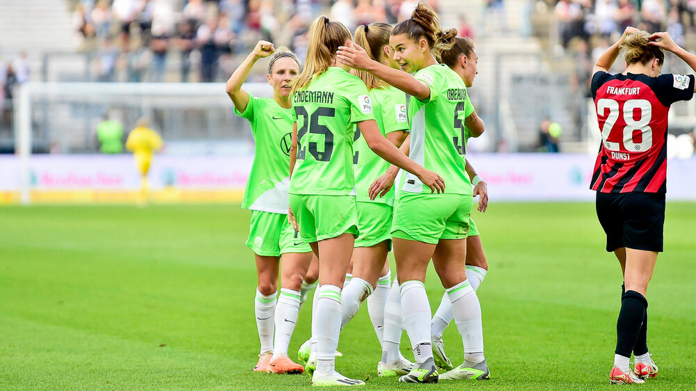 Die VfL Wolfsburg Frauen jubeln und umarmen sich auf dem Spielfeld.