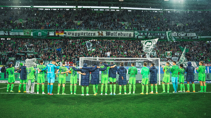 Die Spieler des VfL Wolfsburg liegen sich nach dem Spiel in den Armen und feiern mit den Fans.