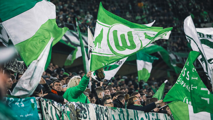 Die Fans schwenken die VfL Wolfsburg-Fahnen.