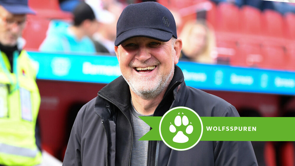 Der VfL Wolfsburg-Geschäftsführer Jörg Schmadtke lacht in die Kamera.