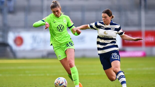 Jule Brand vom VfL Wolfsburg läuft mit dem Ball am Fuß und wird dabei von einer Gegenspielerin des MSV Duisburg bedrängt.