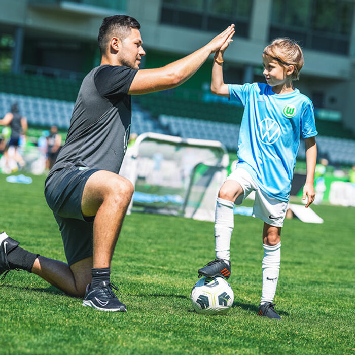 Ein Vater klatscht mit sienem Sohn während einer Aktion der VfL-Fußballschule des VfL Wolfsburg ein. 