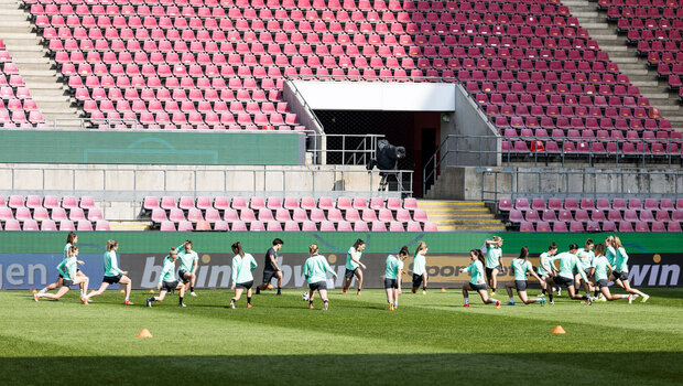 Die Spielerinnen vom VfL Wolfsburg dehnen sich im Stadion.