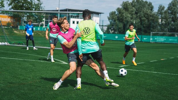 VfL-Wolfsburg-Spieler Nicolas Cozza und Ridle Baku kämpfen im Training um den Ball.