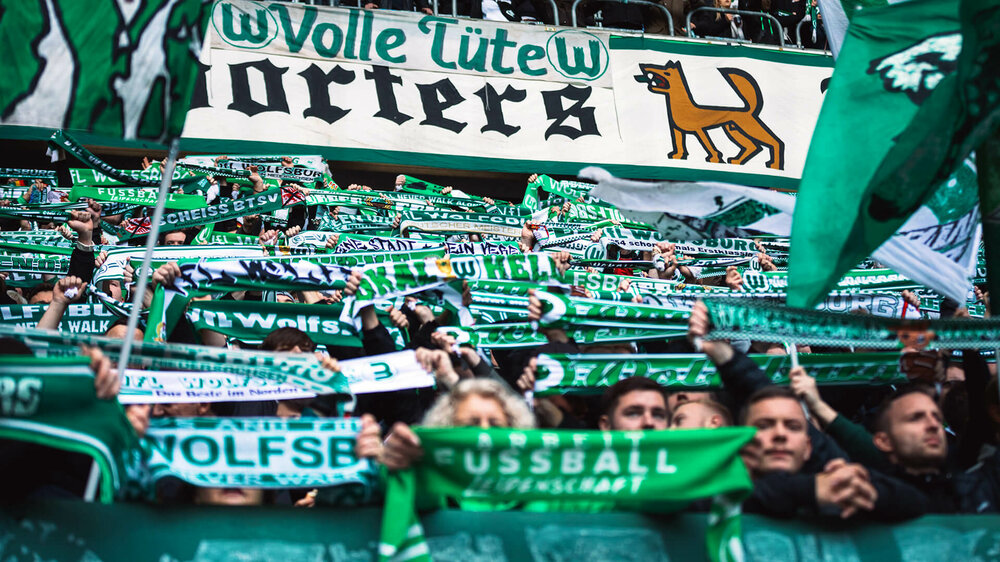 Die VfL-Wolfsburg-Fans halten ihre Schals nach oben.