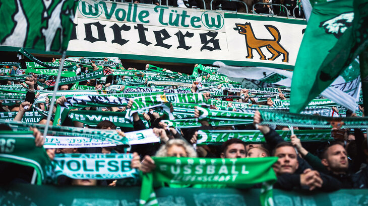 Die VfL-Wolfsburg-Fans halten ihre Schals nach oben.