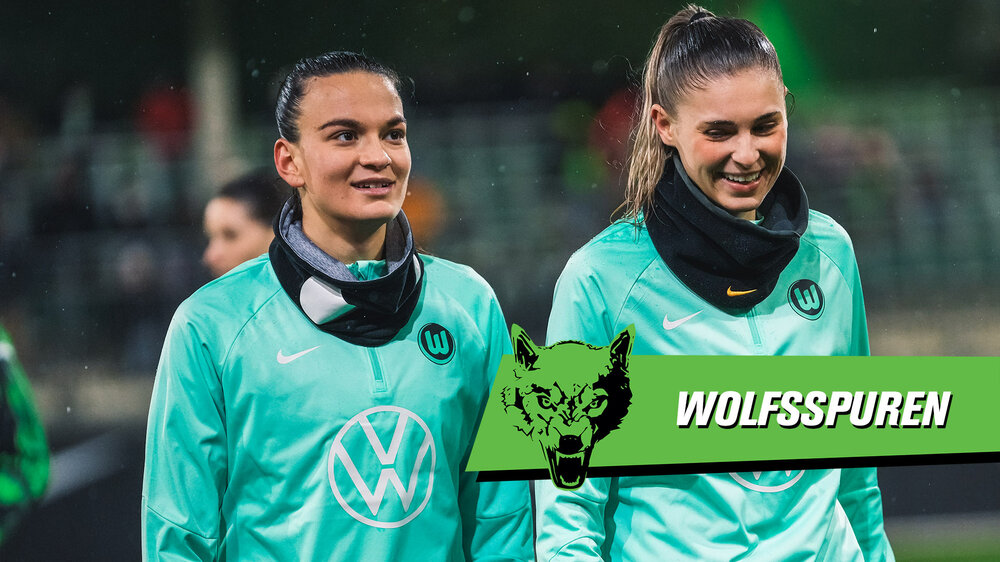 Die beiden VfL-Wolfsburg-Spielerinnen Riola Xhemaili und Jule Brand gehen lachend nebeneinader her. Daneben ist der Schriftzug "Wolfsspuren".