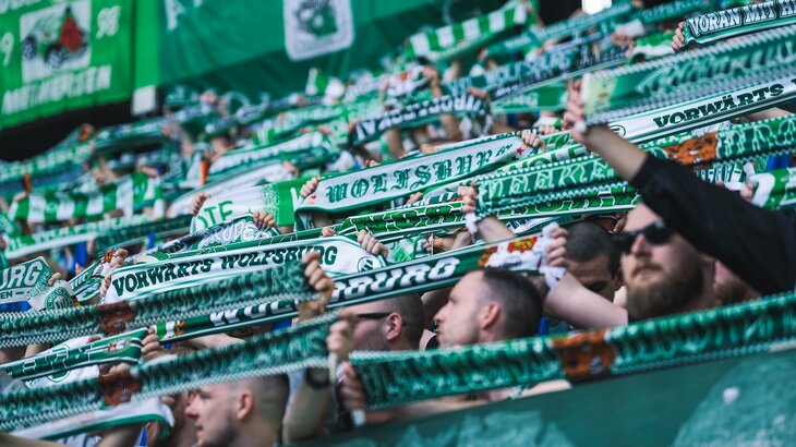 Fans des VfL Wolfsburg strecken grün-weiße Fanschals in die Höhe.