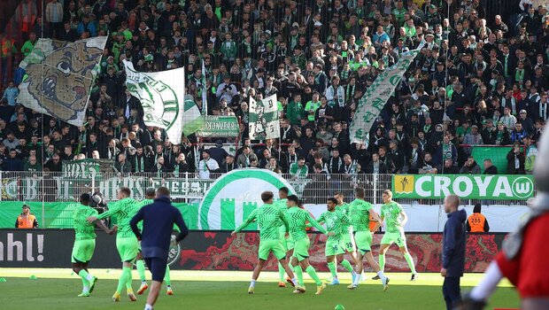 Die Spieler des VfL Wolfsburg wärmen sich vor ihren Fans auf.
