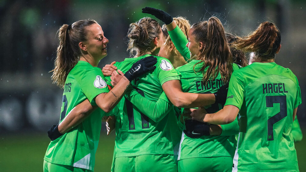 Die Spielerinnen des VfL Wolfsburg liegen sich nach einem Tor jubelnd im Arm.