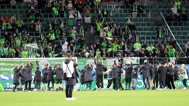 Die VfL-Spielerinnen gewinnen gegen Bayern das DFB-Pokalfinale. Das Foto zeigt die Spielerinnen jubelnd in einer Reihe vor der Fan-Kurve.