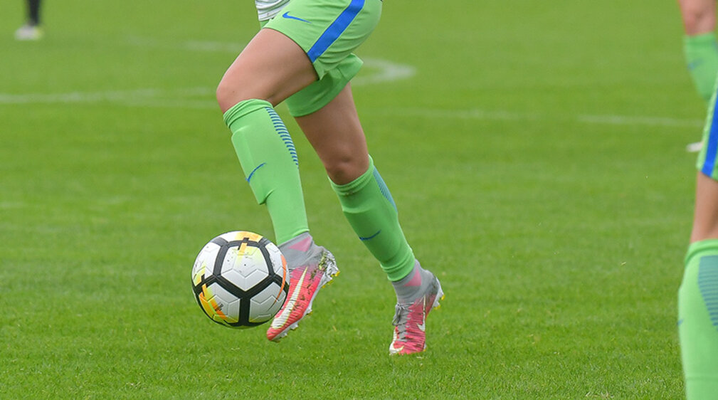 Die Beine einer VfL Spielerin mit Ball am Fuß.