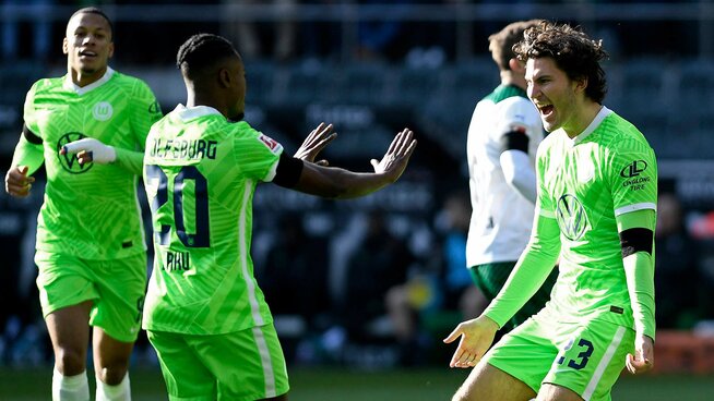 Die VfL Wolfsburg Spieler Ridle Baku und Jonas Wind jubeln zusammen.