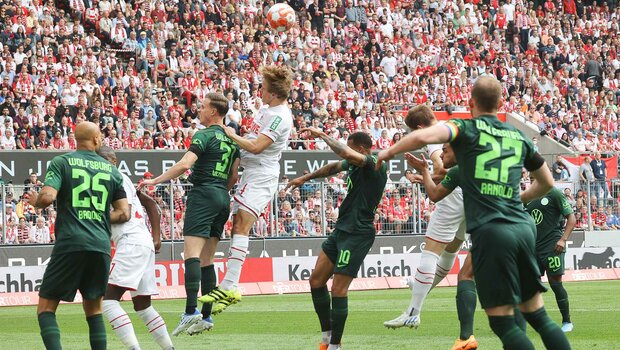 Die Spieler des VfL Wolfsburg und Gegenspieler springen nach einer Hereingabe für einen Kopfball in die Höhe.