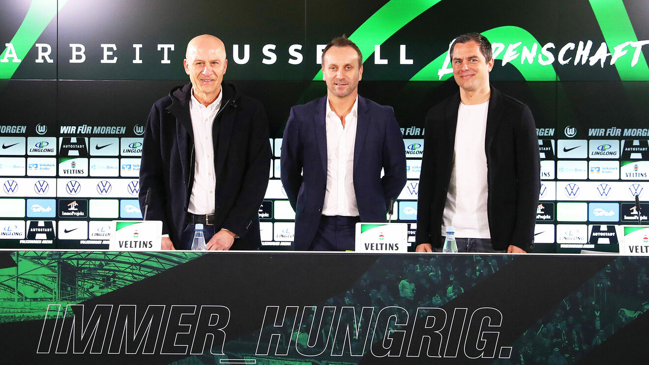 VfL Wolfsburg's Führungduo Schindzielorz und Schäfer, stehen zusammen mit Frank Witter auf dem Podium bei einer Pressekonferenz.