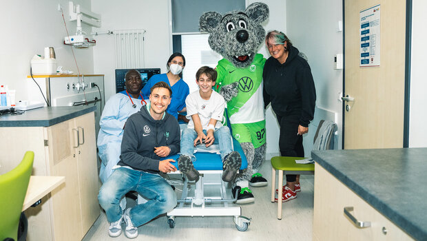 VfL-Wolfsburg-Spieler Kilian Fischer besucht gemeinsam mit Wölfi das Kinderkrankenhaus. Im Bild ist er zu sehen mit einem Patienten, seinem Arzt und einer Krankenschwester. 
