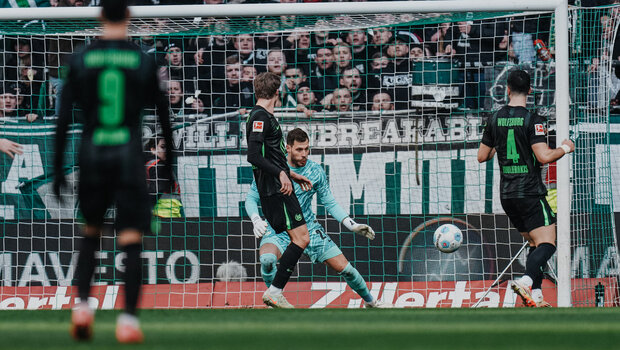 VfL-Wolfsburg-Torwart Marius Müller geht in die Hocke und visiert einen heranfliegenden Ball an.