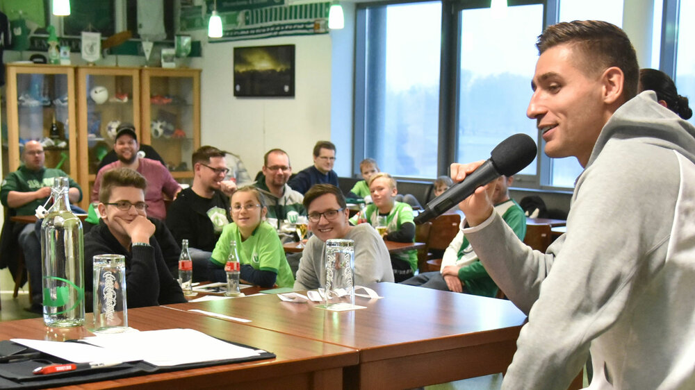 VfL Wolfsburg Torwart Koen Casteels hält ein Mikrofon in der Hand und beantwortet den Mitgliedern aus dem Wölfeclub Fragen im Wölfeclub-Talk.