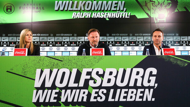 VfL Wolfsburg Trainer Hasenhüttl, Sportdirektor Schindzielorz und die Pressesprecherin sitzen bei einer Pressekonferenz nebeneinander.