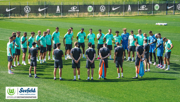 Die Spieler des VfL Wolfsburg stehen im Kreis auf dem Platz im Trainingslager und lauschen einer Ansprache des Trainers.