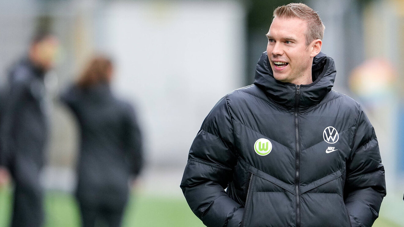 VfL Wolfsburg Frauen-Trainer Stroot steht gut gelaunt am Spielfeldrand.
