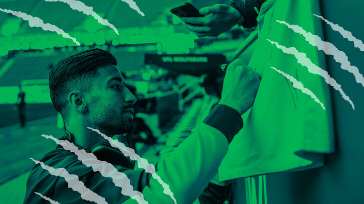 VfL-Wolfsburg-Spieler Mohamed Amoura unterschreibt ein Trikot.