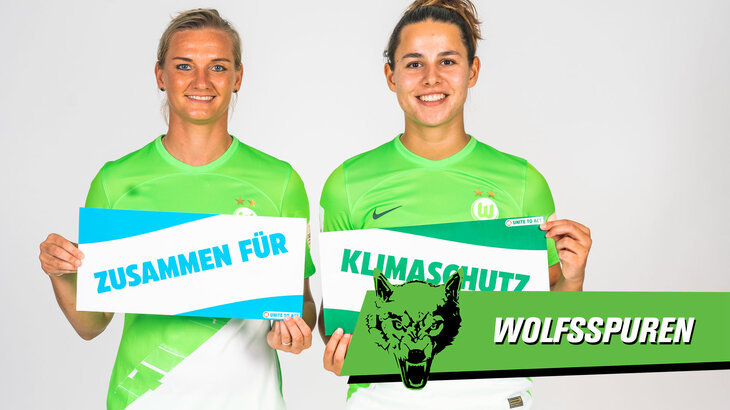 Die Spielerinnen des VfL Wolfsburg Popp und Oberdorf mit Schildern zum Klimaschutz.