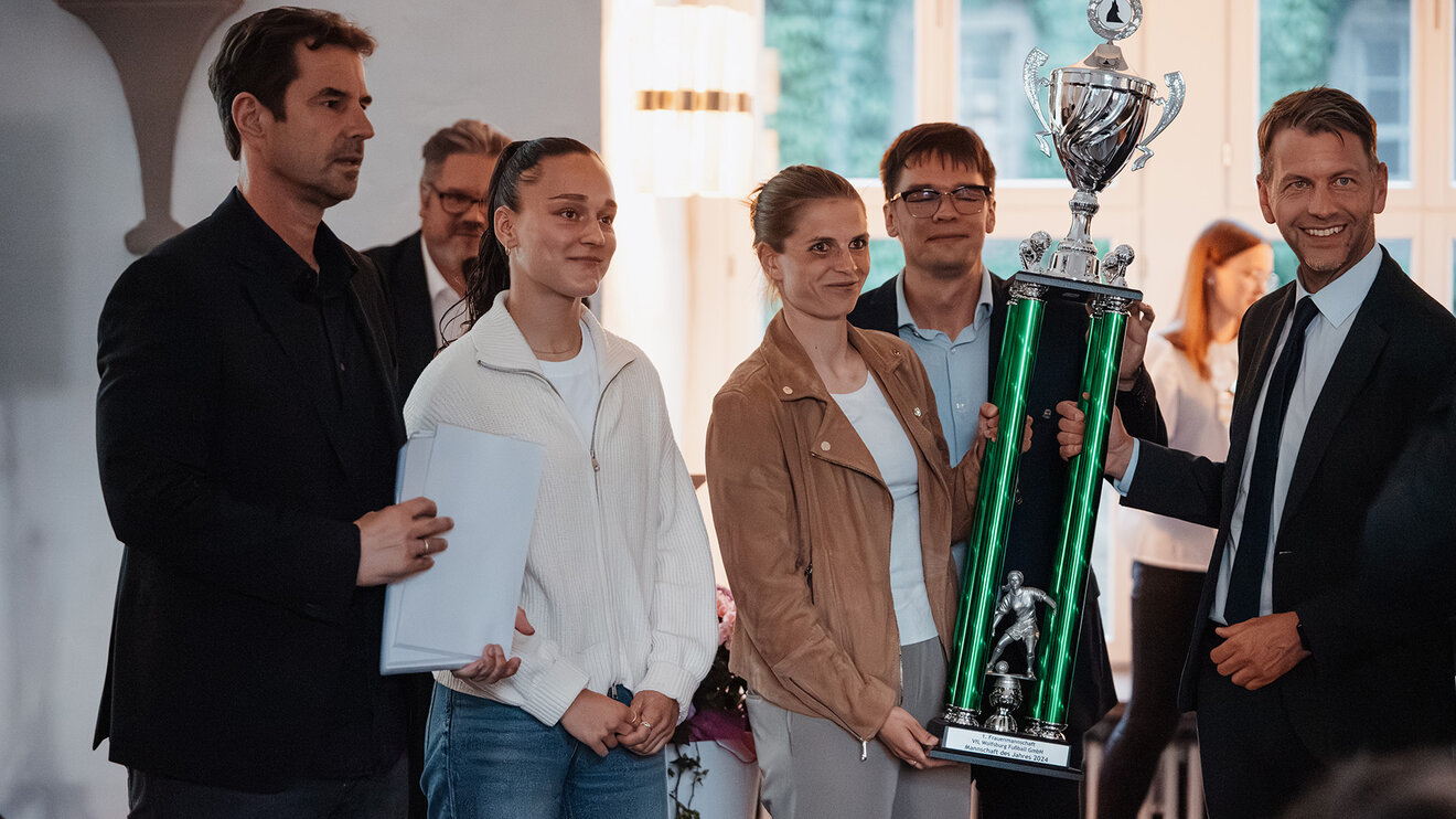 Spielerinnen Tabea Sellner und Diana Nemeth sowie Direktor Frauenfußball Ralf Kellermann vom VfL Wolfsburg nehmen den Pokal, der Ihnen Oberbürgermeister Dennis Weilmann überreicht entgegen.