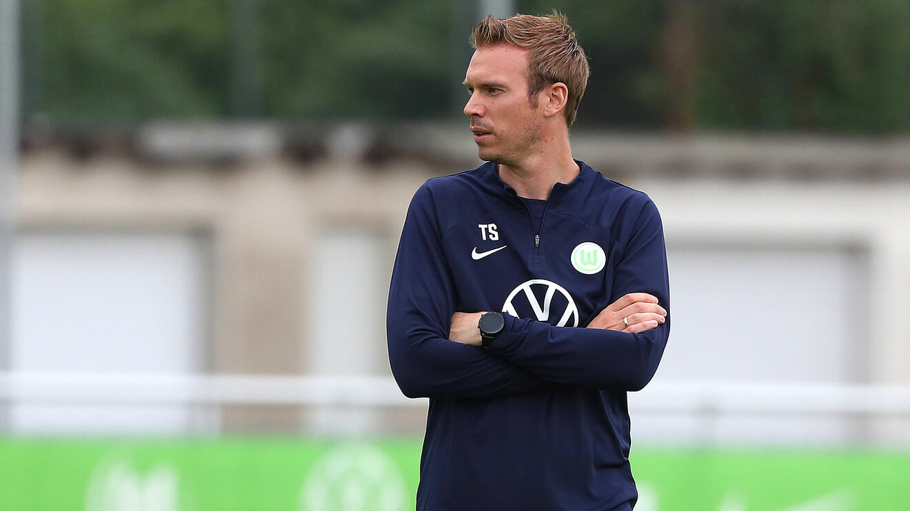 Chefcoach Tommy Stroot schauft sich beim Training mit verschränkten Armen die Fortschritte der Spielerinnen des VfL Wolfsburg an.