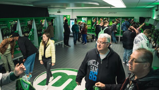Fans schauen sich in der Umkleidekabine die neuen Trikots des VfL Wolfsburg an.
