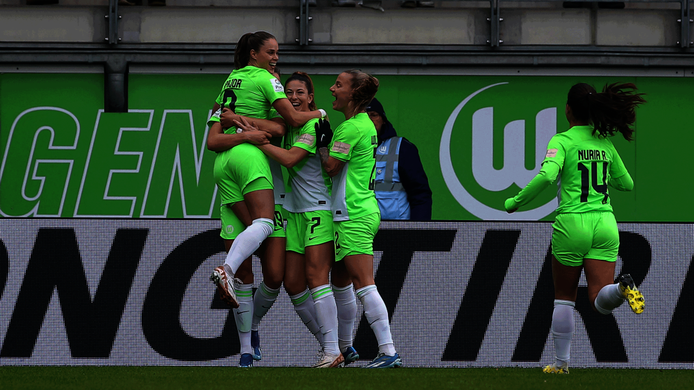 Die Spielerinnen des VfL Wolfsburg stehen jubelnd beisammen.
