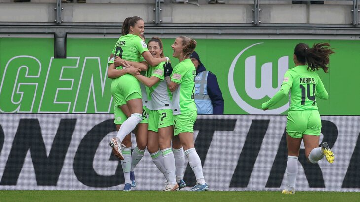 Die Spielerinnen des VfL Wolfsburg stehen jubelnd beisammen.