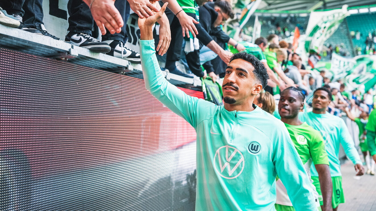 VfL Wolfsburg Spieler Tiago Tomas, Ridle Baku und weitere gehen nach einem Sieg vor der Nordkurve lang und schlagen mit den Fans ein.