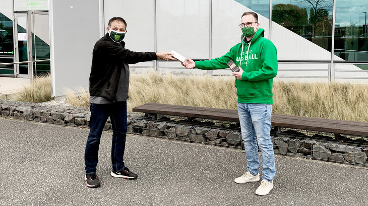 Combridge überreicht VfL-Wolfsburg Smartphone.