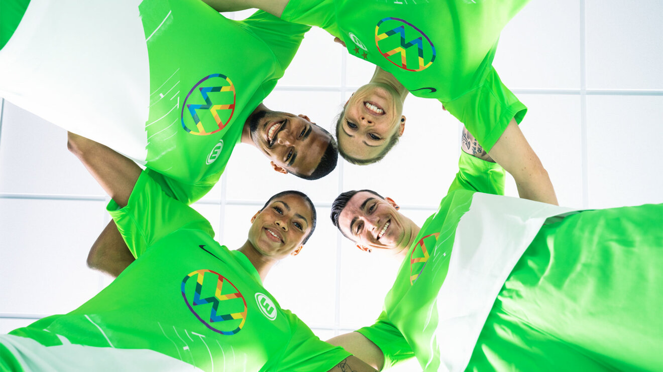 Die Spieler des VfL Wolfsburg schauen von oben in die Kamera, während sie in einem Kreis stehen.