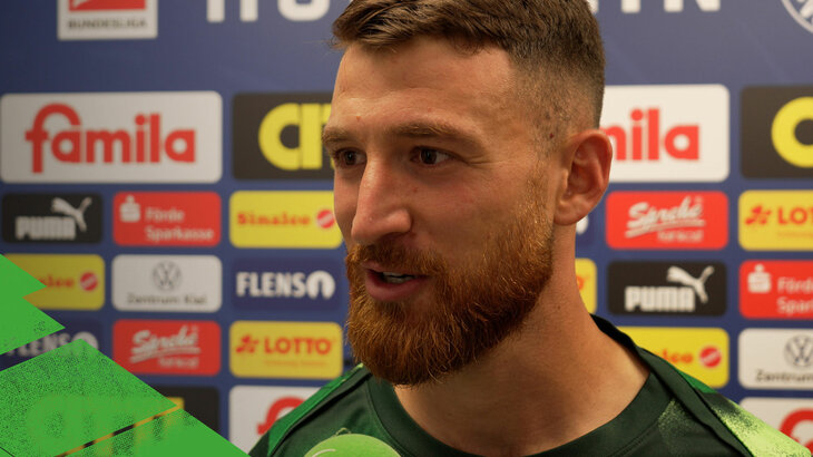 VfL Wolfsburg Spieler Salih Özcan steht vor einer Sponsorenwand und gibt nach einem Spiel ein Interview für Wölfe TV.