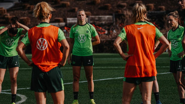 VfL-Wolfsburg-Spielerin Ella Peddemors steht mit ihren Mitspielerinnen in einem Kreis auf dem Trainingsplatz.