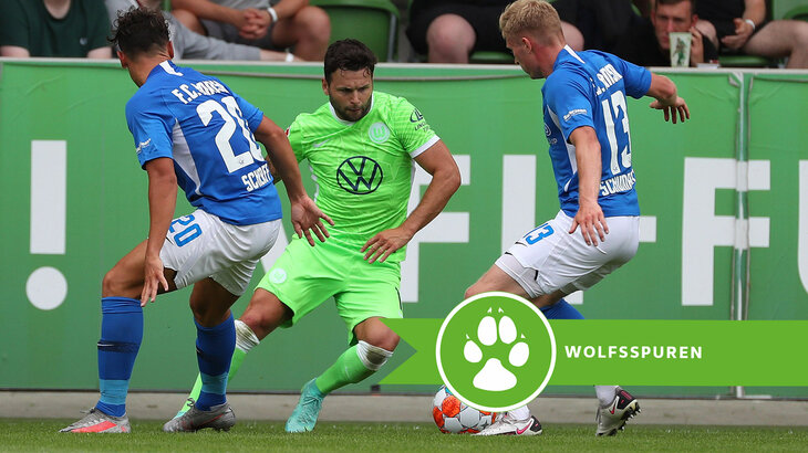 VfL Wolfsburg-Spieler Steffen bei einem Zweikampf mit Gegenspielern. Daneben der Schriftzug Wolfsspuren.