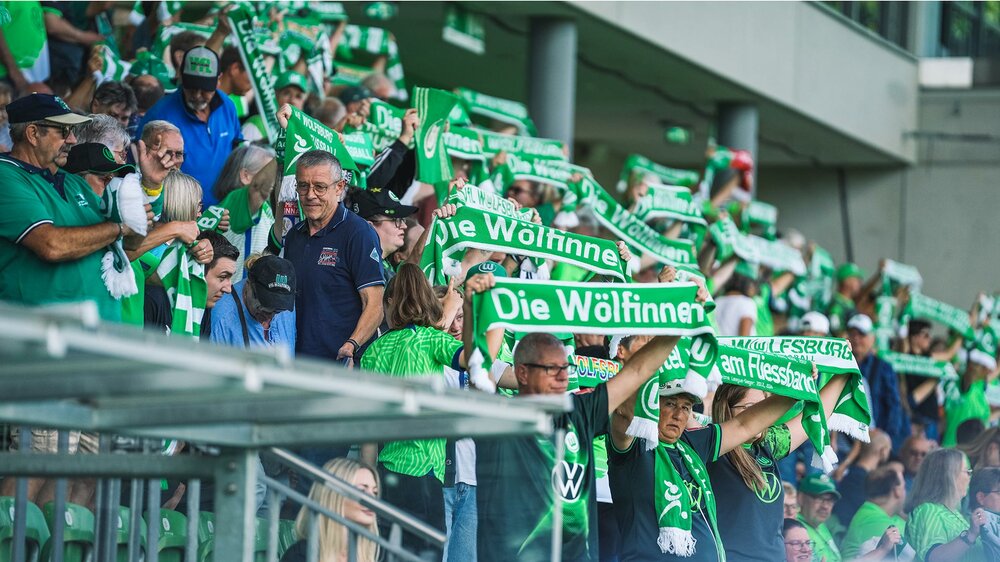 Die Fans der VfL-Wolfsburg-Frauen halten auf der Tribüne ihre Schals in die Höhe.