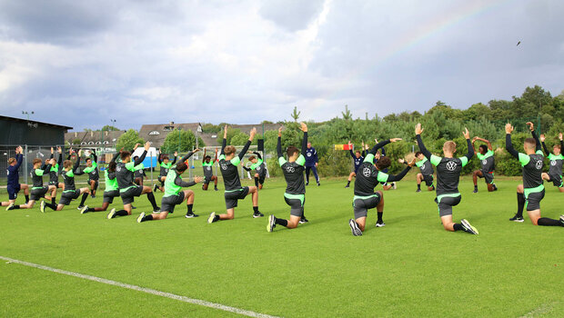VfL Wolfsburg U19-Spieler wärmen sich vor dem Training im Trainingslager in Polen mit einer Stretchübung auf.