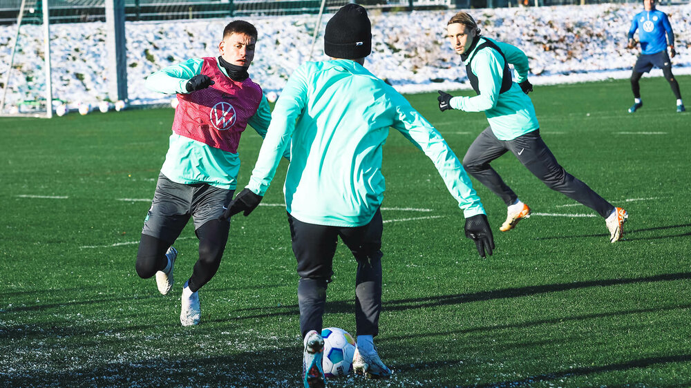 Die Spieler des VfL Wolfsburg trainieren in Winterkleidung auf den Plätzen um die Volkswagen Arena.