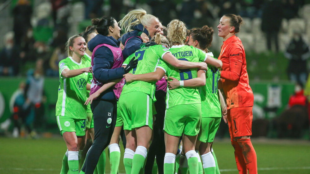 Die Frauen des VfL Wolfsburg jubeln auf dem Platz und umarmen sich gegenseitig in einem großen Kreis nach ihrem Sieg in der UWCL.