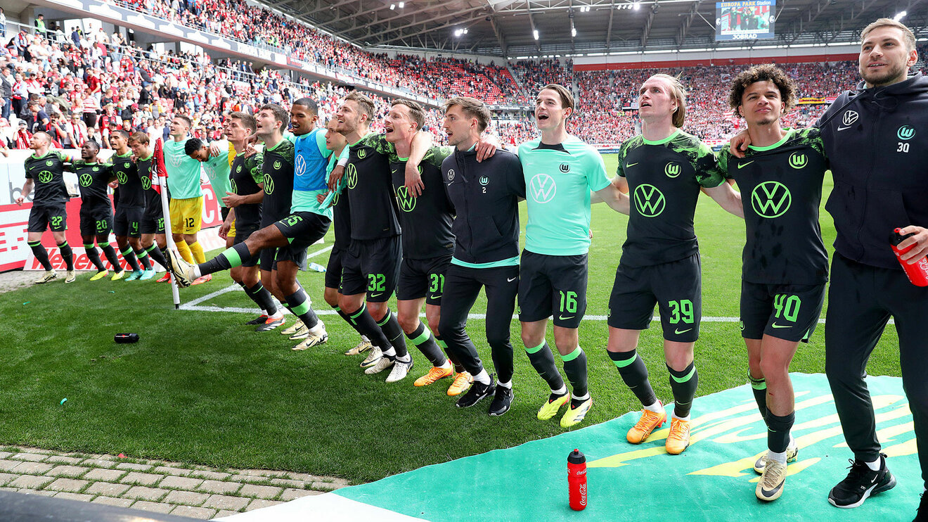 Jubel aller Spieler des VfL Wolfsburg vor der Fankurve nach Abpfiff auf dem Rasens des Stadions des SC Freiburg.
