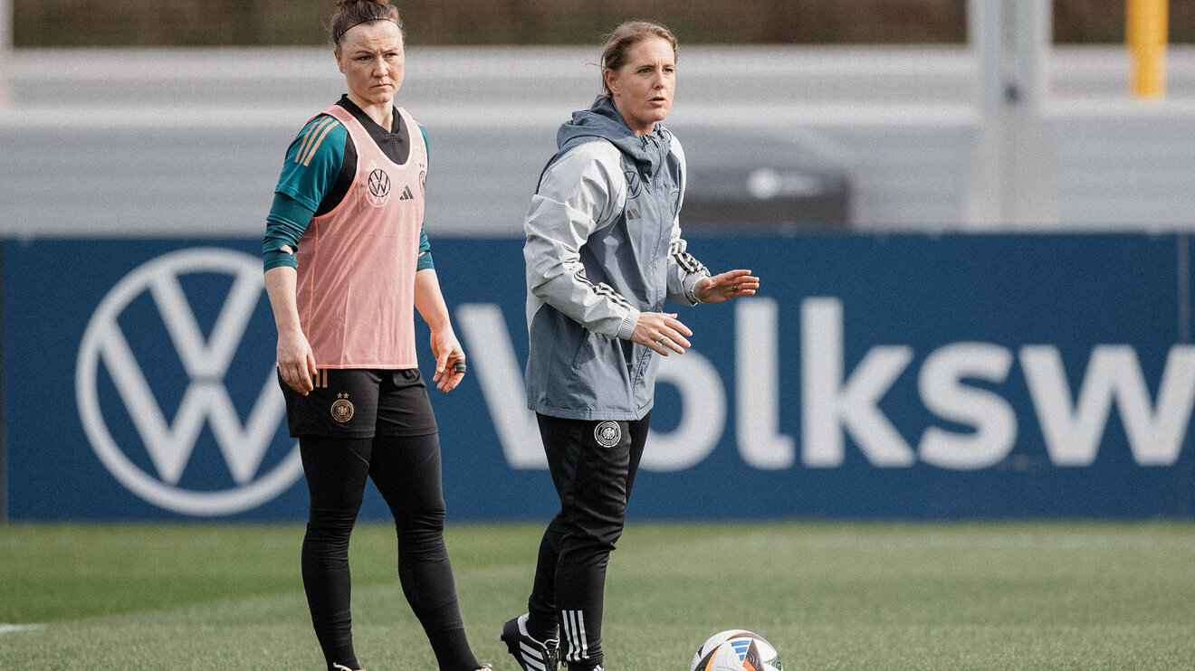 VfL-Wolfsburg-Spielerin Marina Hegering im Trainingsoutfit der Nationalmannschaft steht neben Trainerin Britta Carlson.