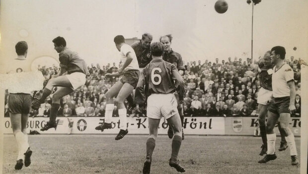 Ein historisches schwarz-weiß-Bild eines Kopfballduelles bei einer Partie des VfL Wolfsburg gegen Kiel.