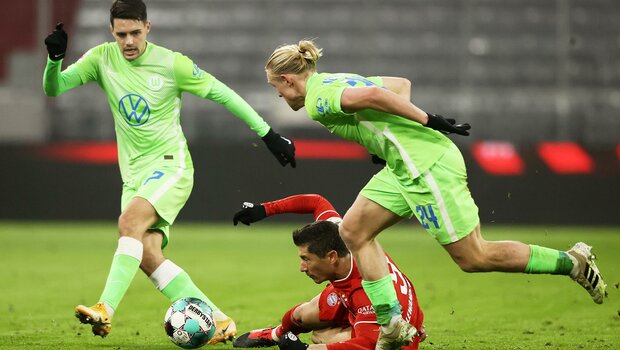 VfL Wolfsburg Spieler Brekalo und Schlager im Kampf um den Ball gegen Robert Lewandowski von Bayern München.