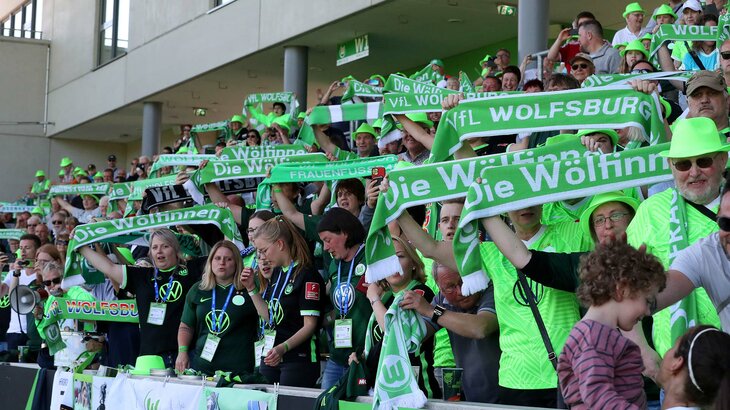 Fans der VfL-Wolfsburg Frauen schwenken Schals im AOK Stadion.